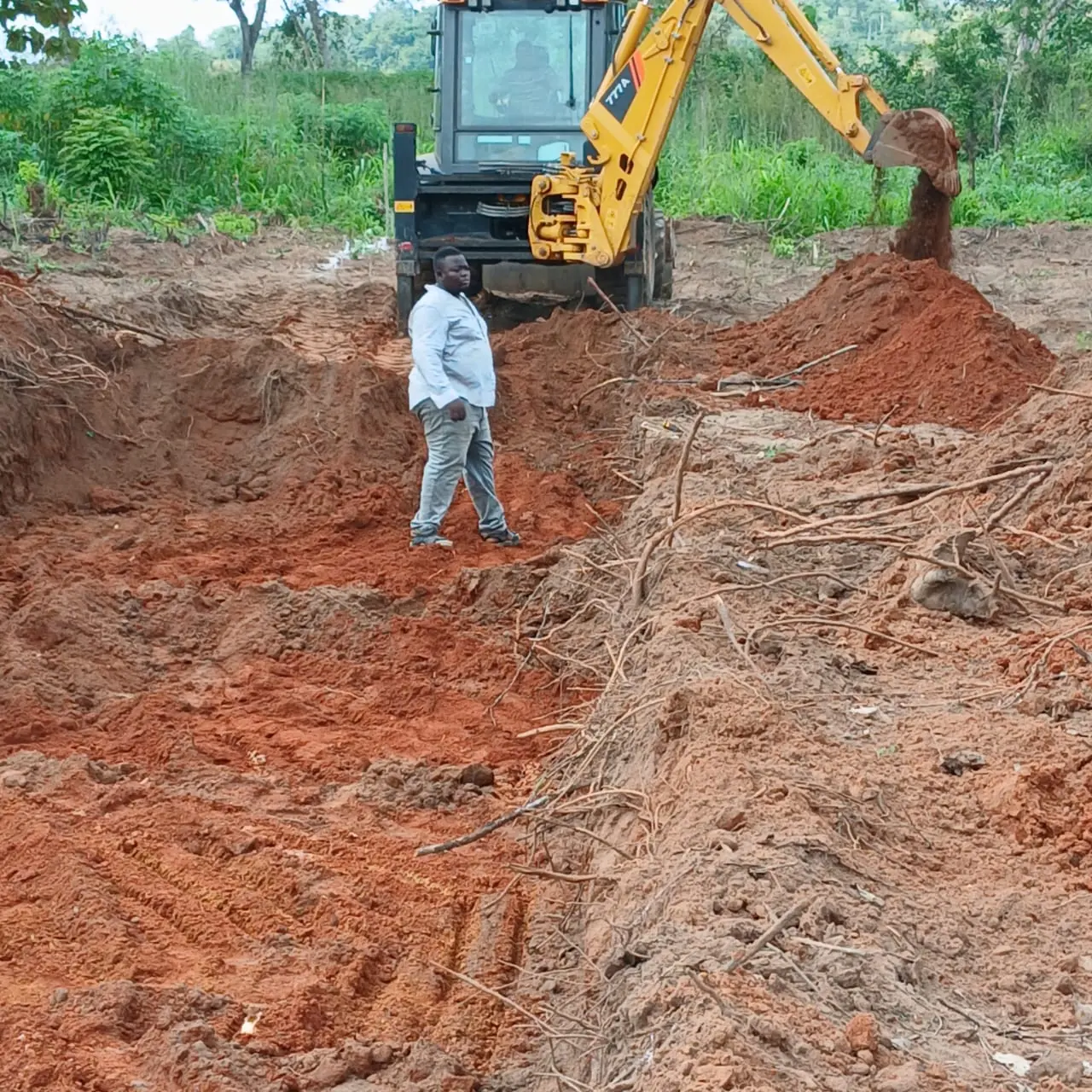 Excavator moving red earth on construction site
